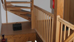 Een houten spiraaltrap met een telefoon en een kleine zwarte tas op de verdieping.
