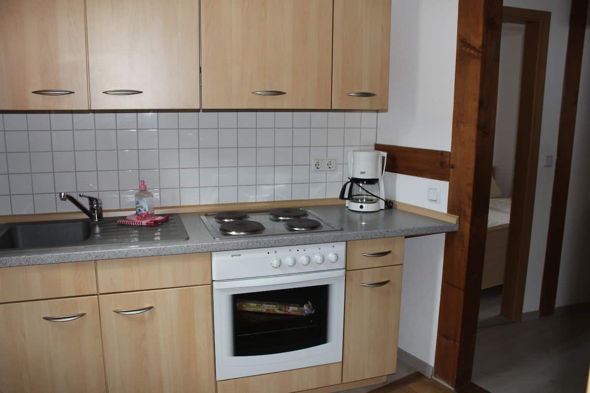 Een keuken met houten kastjes, een roestvrijstalen spoelbak, een fornuis en een koffiezetapparaat.