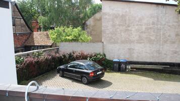 A car parked in a driveway with a house and a wall in the background.