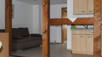 Ein modernes Wohnzimmer mit einer Couch, Holzbalken und einer Küchenzeile mit Holzausstattung.