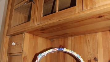 Un gabinete de madera con puertas de vidrio, un cuenco blanco y un cajón.