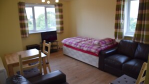 A room with a bed, a sofa, a chair, a table, and a TV. - granary (London)