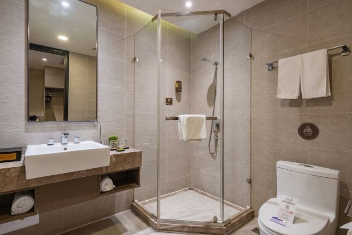 A modern bathroom with a glass-enclosed shower, a white sink, and a toilet.