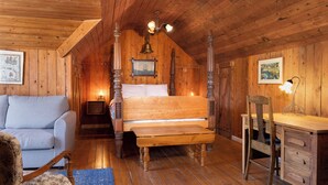 Ein Zimmer mit Holzboden, einem Bett, einem Schreibtisch, einem Sessel und einer Couch.