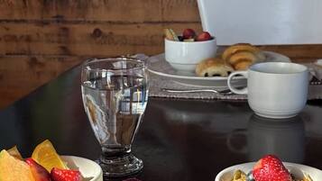 A breakfast setting with a glass of water, bowls of fruit, eggs, and a cup of coffee on a table.