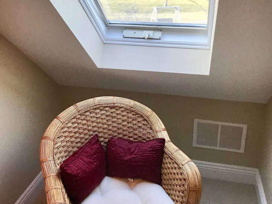 A room with a skylight, a wicker chair with cushions, and a radiator.