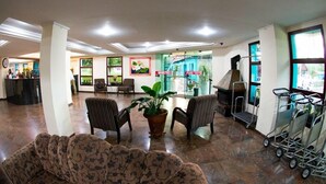 Eine geräumige Lobby mit Empfangstresen, bequemen Sitzgelegenheiten, einer Zimmerpflanze und einer Grillstation.