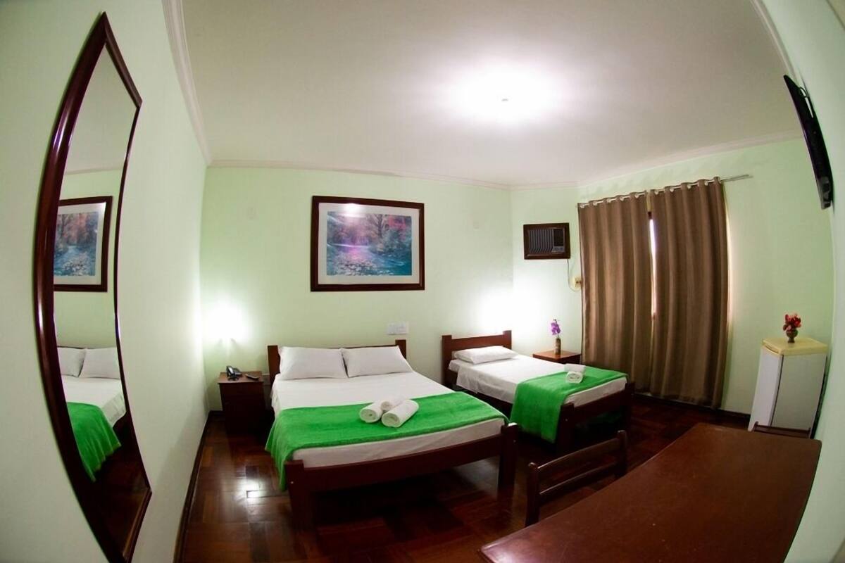 Une chambre d’hôtel avec deux lits, un bureau, une chaise, un miroir et un tableau au mur.