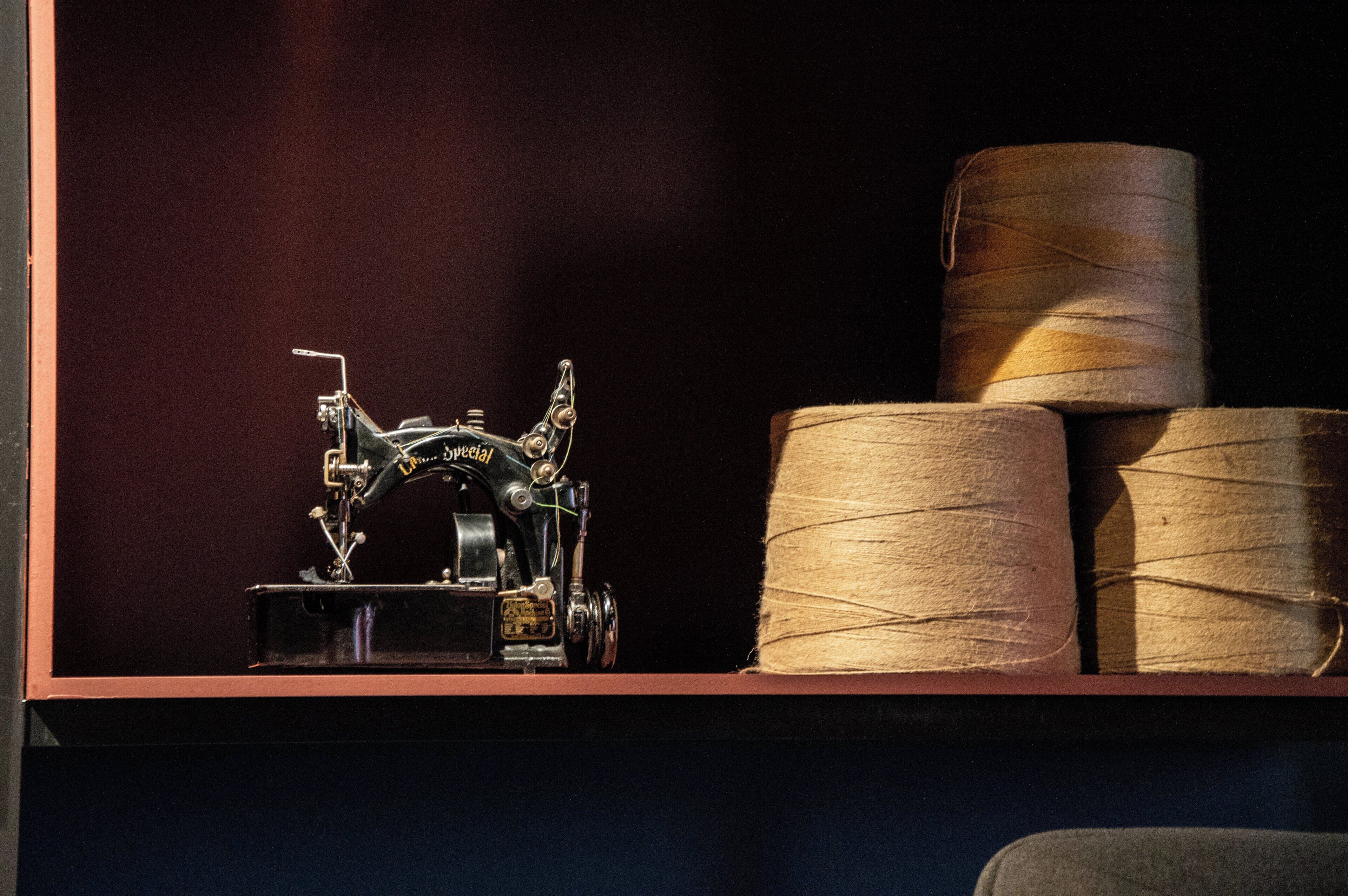 A sewing machine and spools of thread on a shelf.