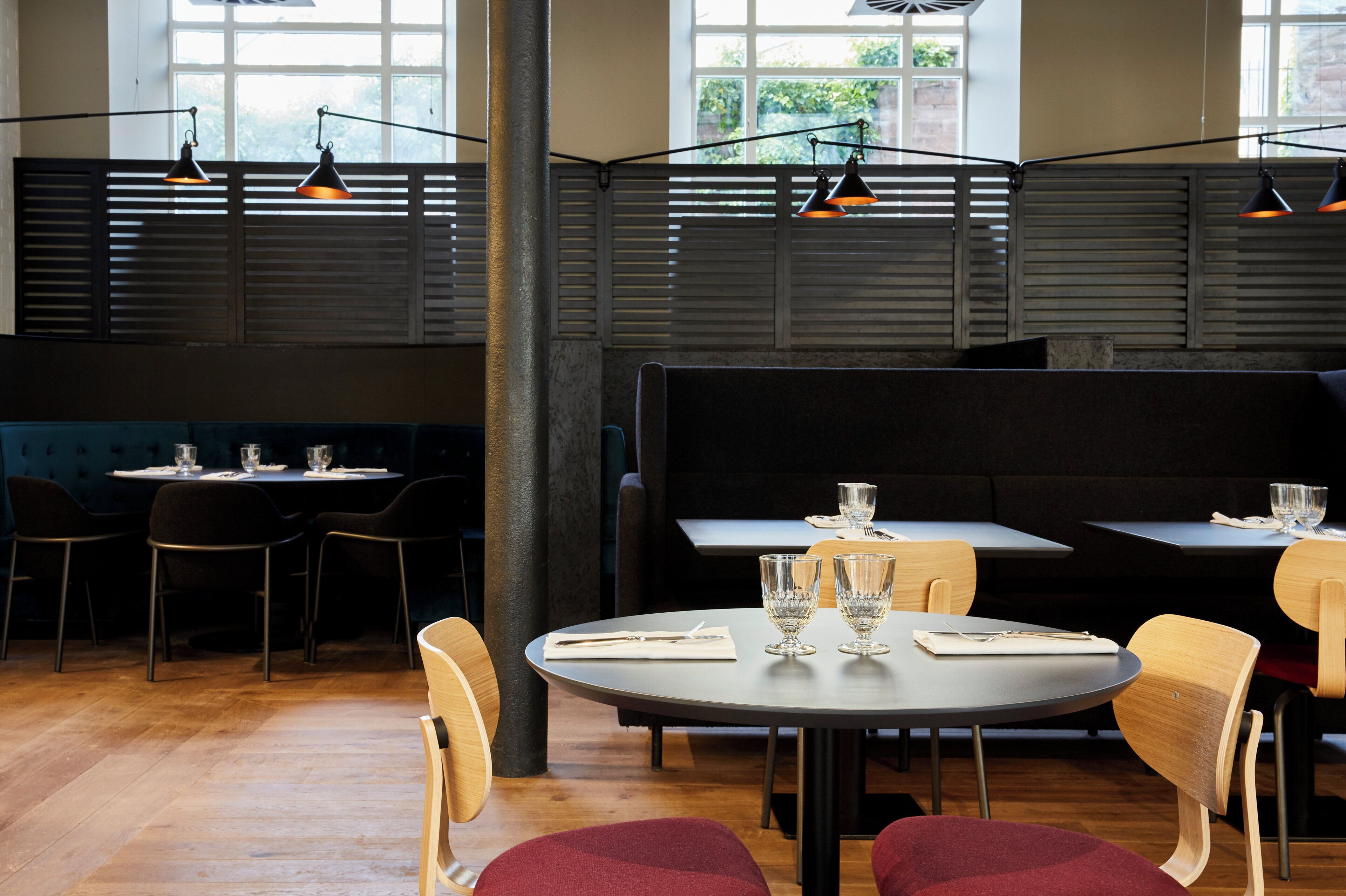 Ein Restaurantinneres mit runden Tischen, Stühlen und Pendelleuchten.