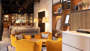 A modern bar area with a bar counter, shelves with bottles, and a seating area with yellow chairs and a sofa. - Hotel Indigo Dundee by IHG (Dundee)