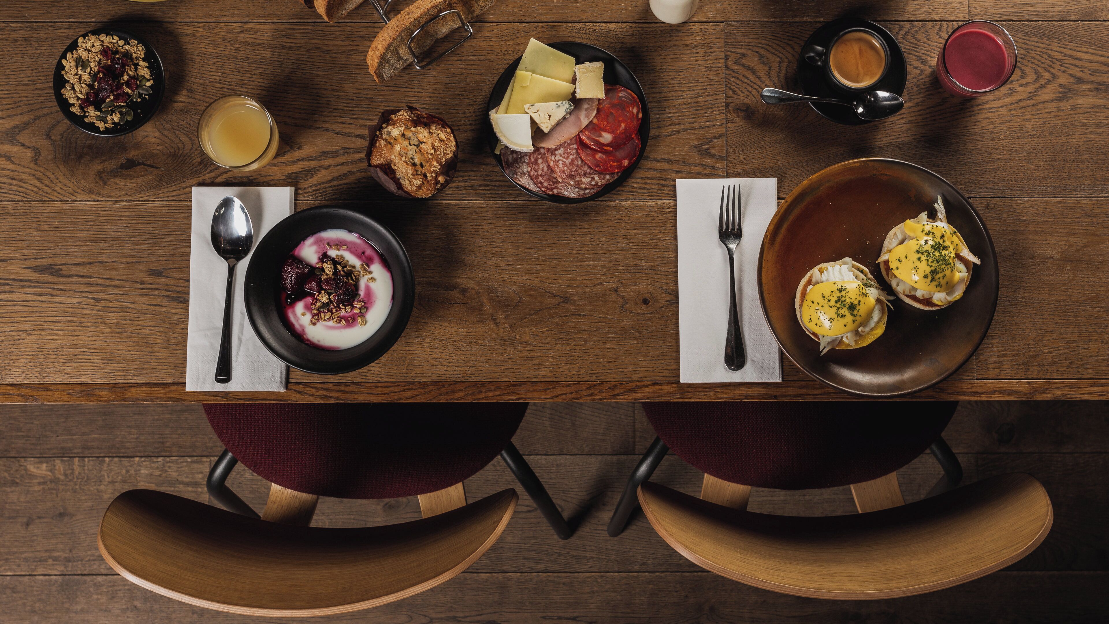 A wooden dining table with various food items and utensils.