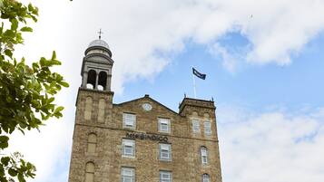 A historic building with a clock tower, a flag, and the name "Hotel Indigo" on the facade.