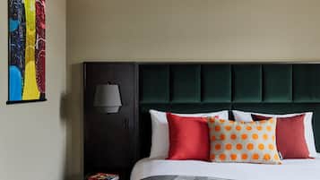 A hotel room with a bed, a nightstand, a lamp, and a colorful artwork on the wall.