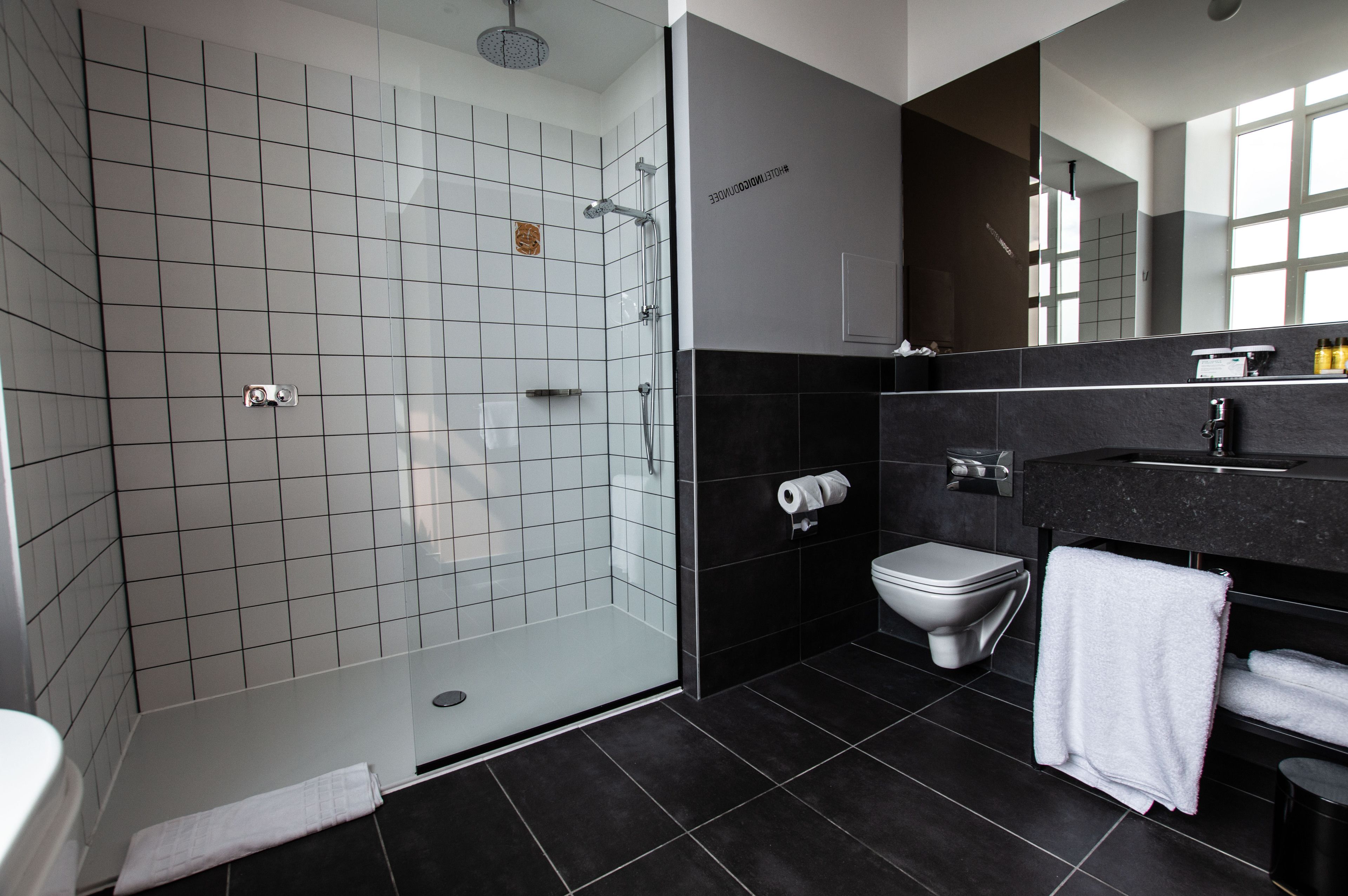 A modern bathroom with a glass-enclosed shower, a toilet, and a vanity with a mirror.