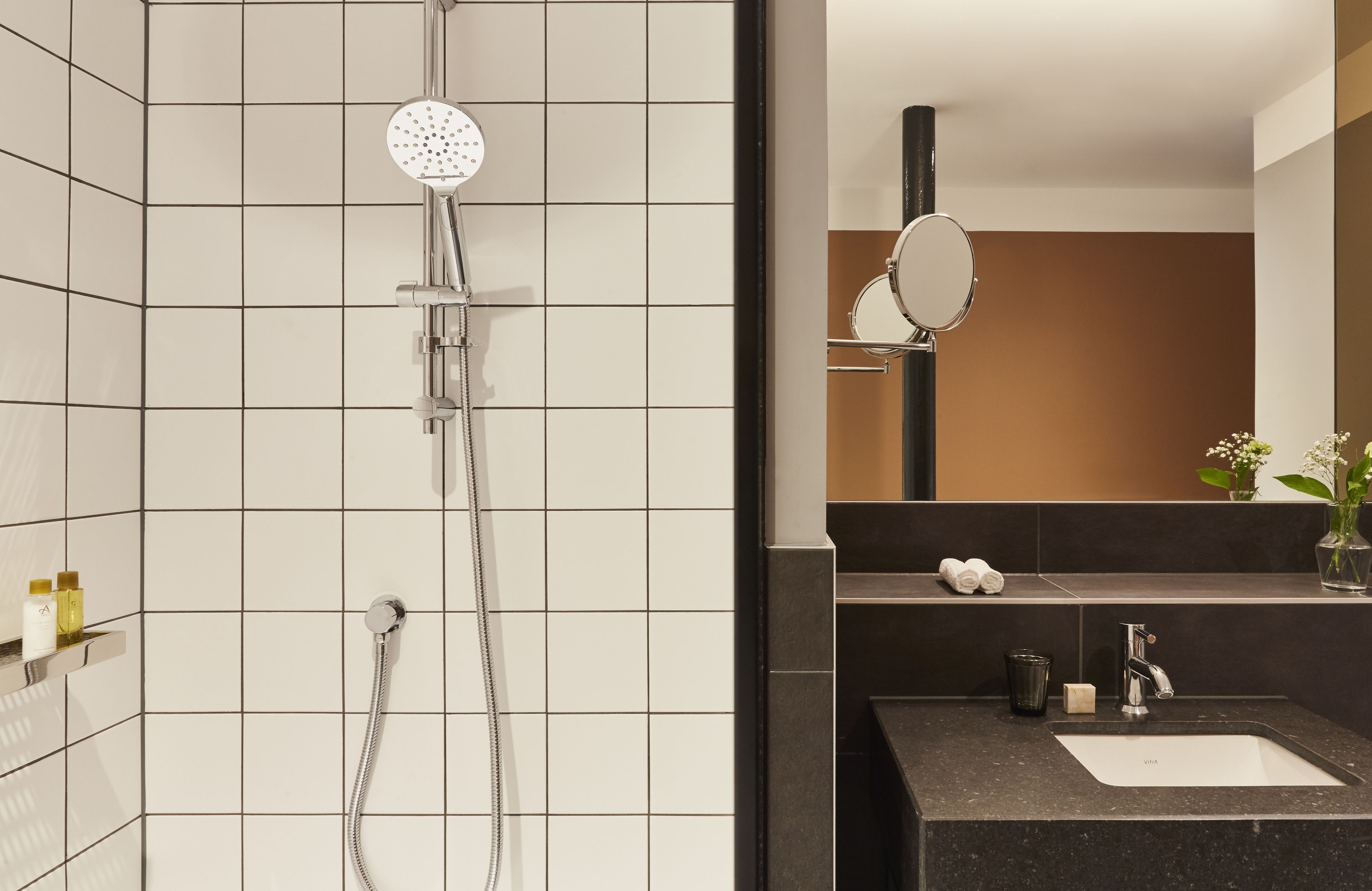 Een moderne badkamer met een douche, wastafel en spiegel.