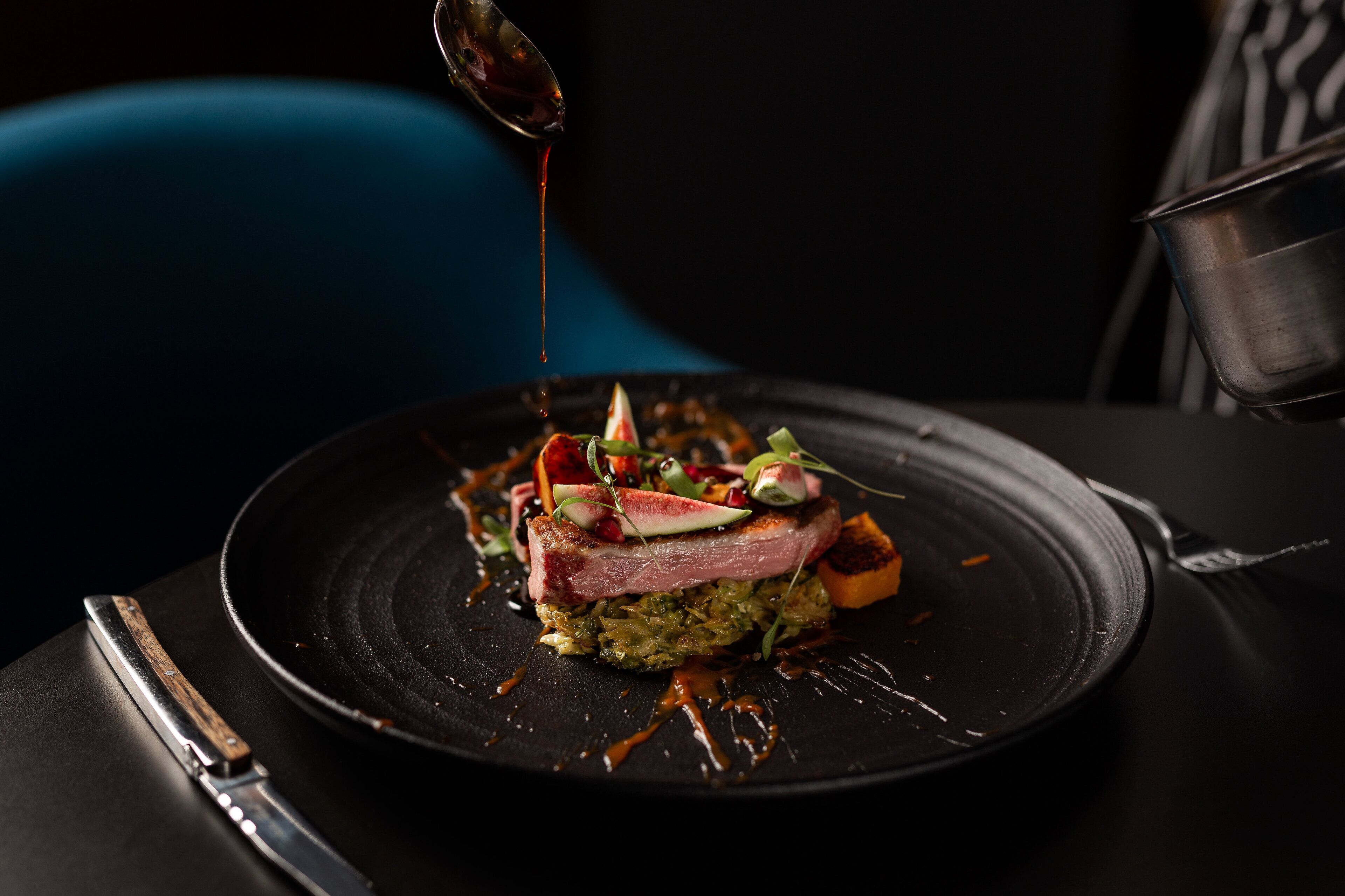 Une assiette noire avec une portion de nourriture, une cuillère et une fourchette, le tout posé sur une table.