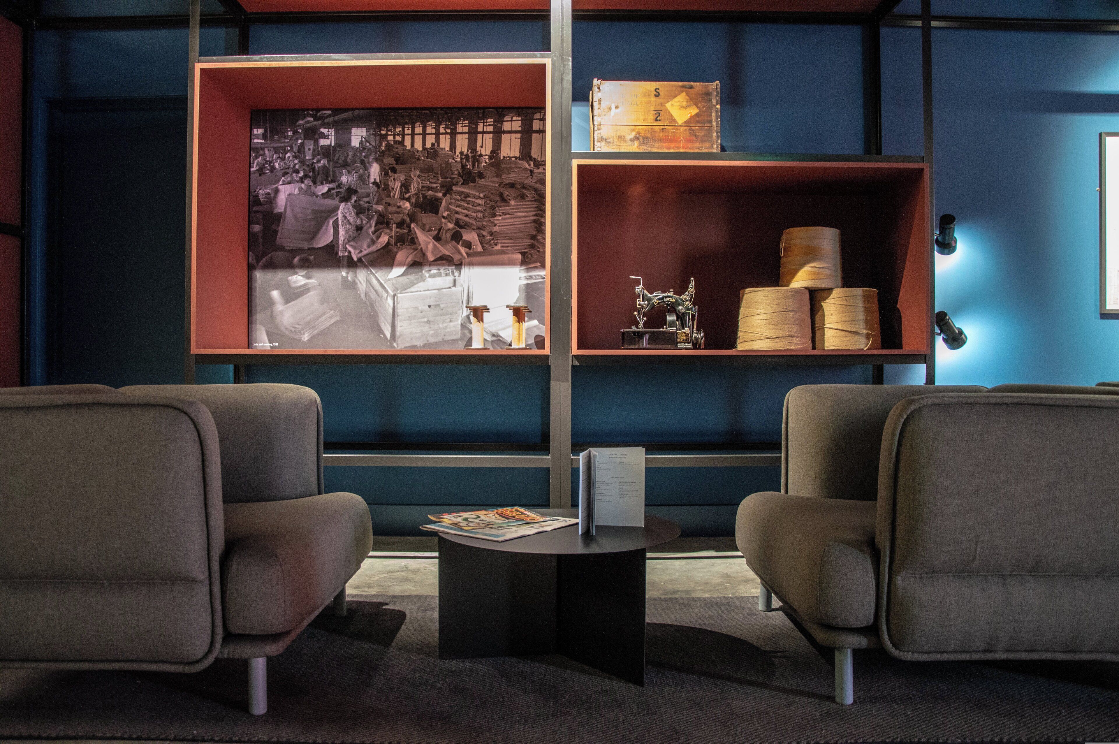 A room with two armchairs, a table with a magazine, and a large window displaying a vintage photo.