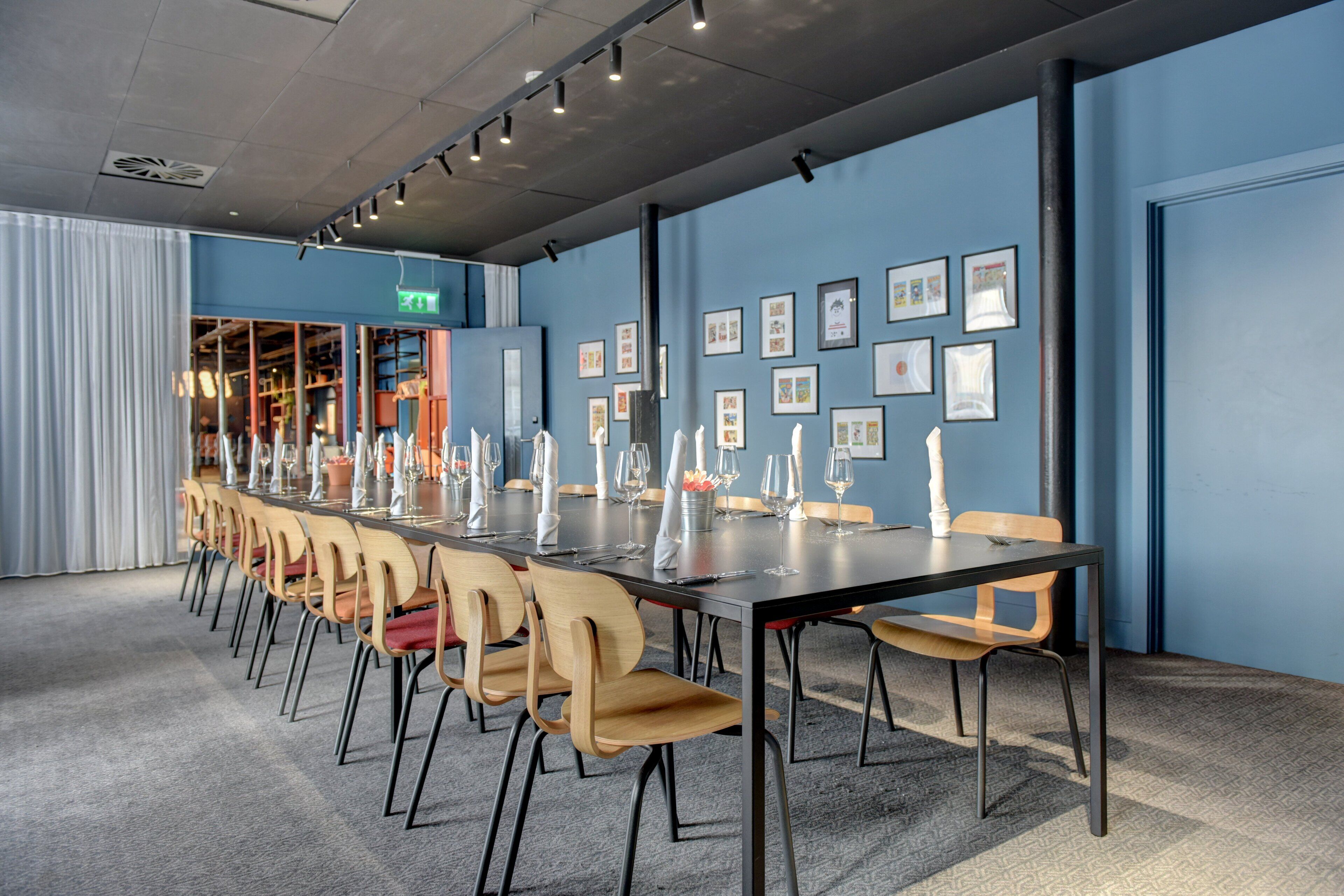 A conference room with a long table, chairs, and framed pictures on the wall.