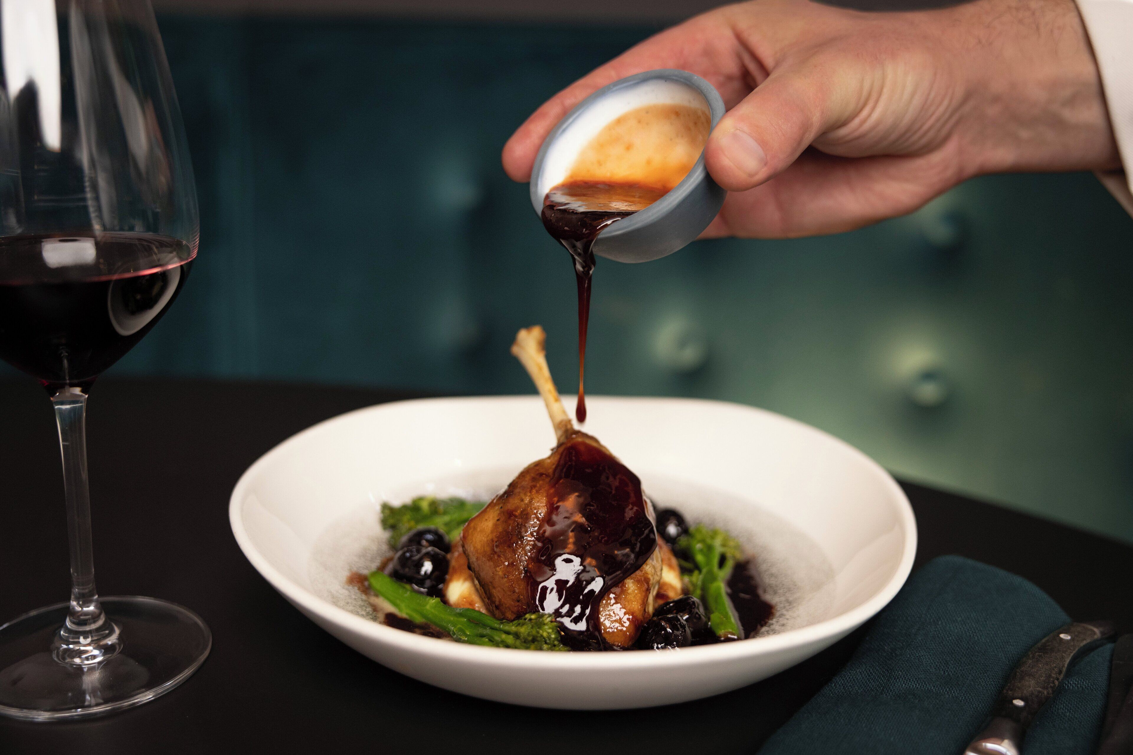 A dining table with a plate of food, a wine glass, and a knife.