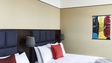 Habitación de hotel con dos camas, techo de madera, lámpara de pared y un cuadro abstracto de colores.