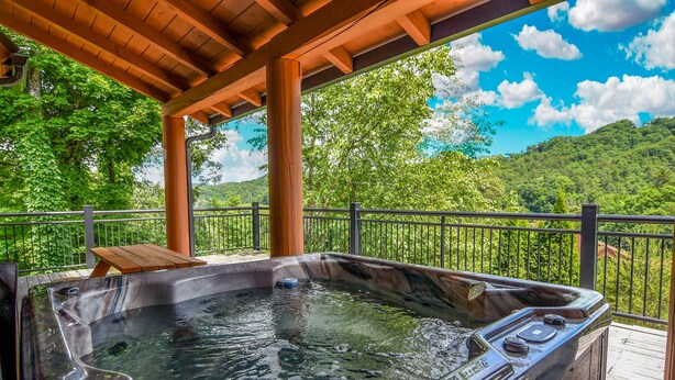 A hot tub under a wooden pergola with a view of lush greenery and hills. - Moose Hollow Lodge (Sevierville)