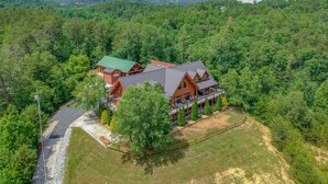 A lodge with a large deck and multiple rooms, surrounded by dense forest and hills. - Moose Hollow Lodge (Sevierville)