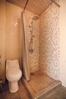 Un baño con ducha, inodoro y paredes de azulejos.