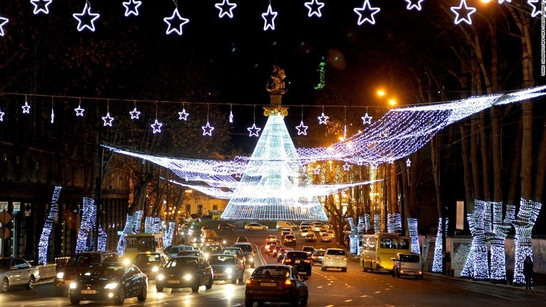 A street at night with illuminated stars and a large, illuminated structure in the center.