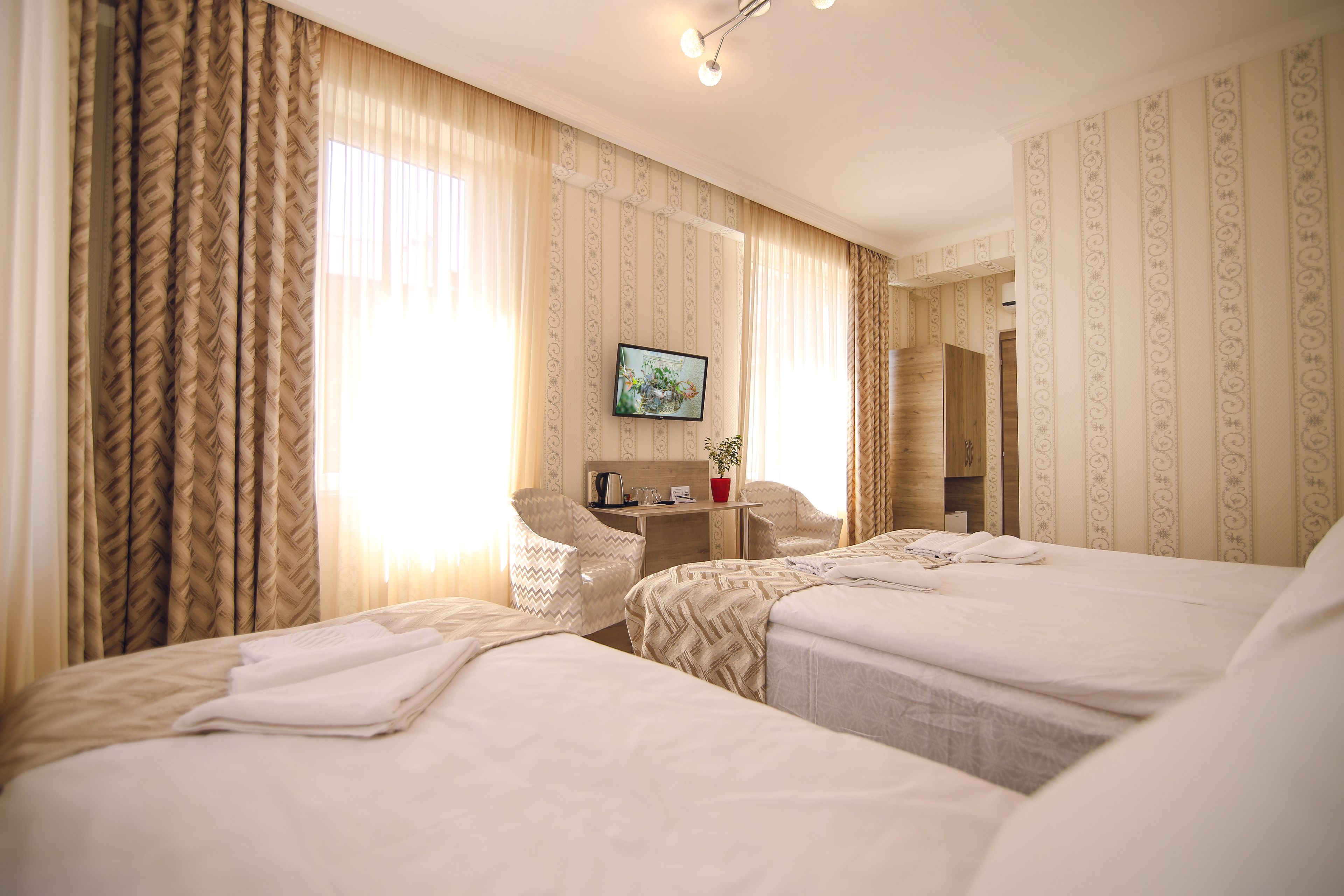 A hotel room with two beds, a desk, and a TV.