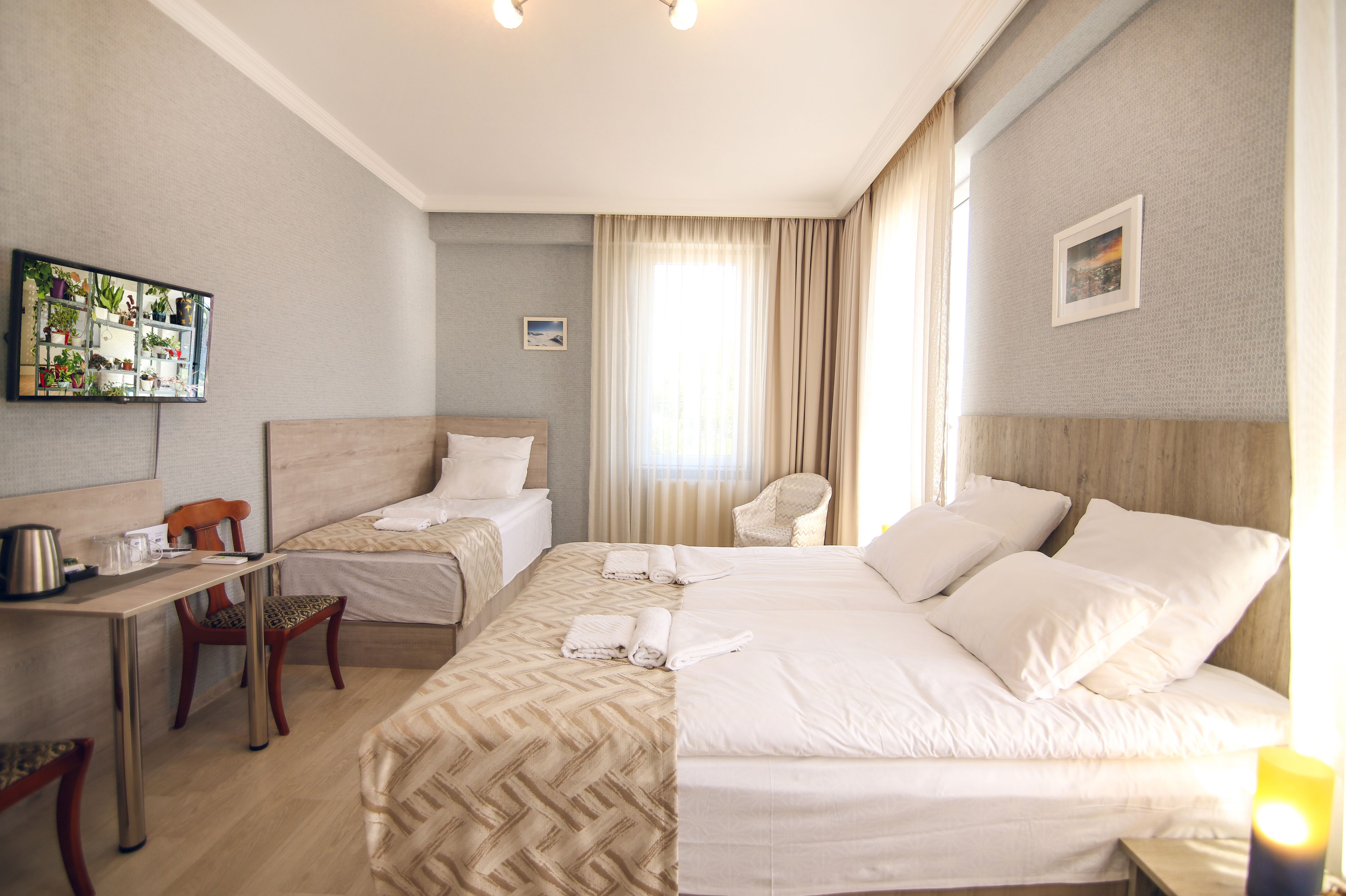 A hotel room with two beds, a desk, and a chair.