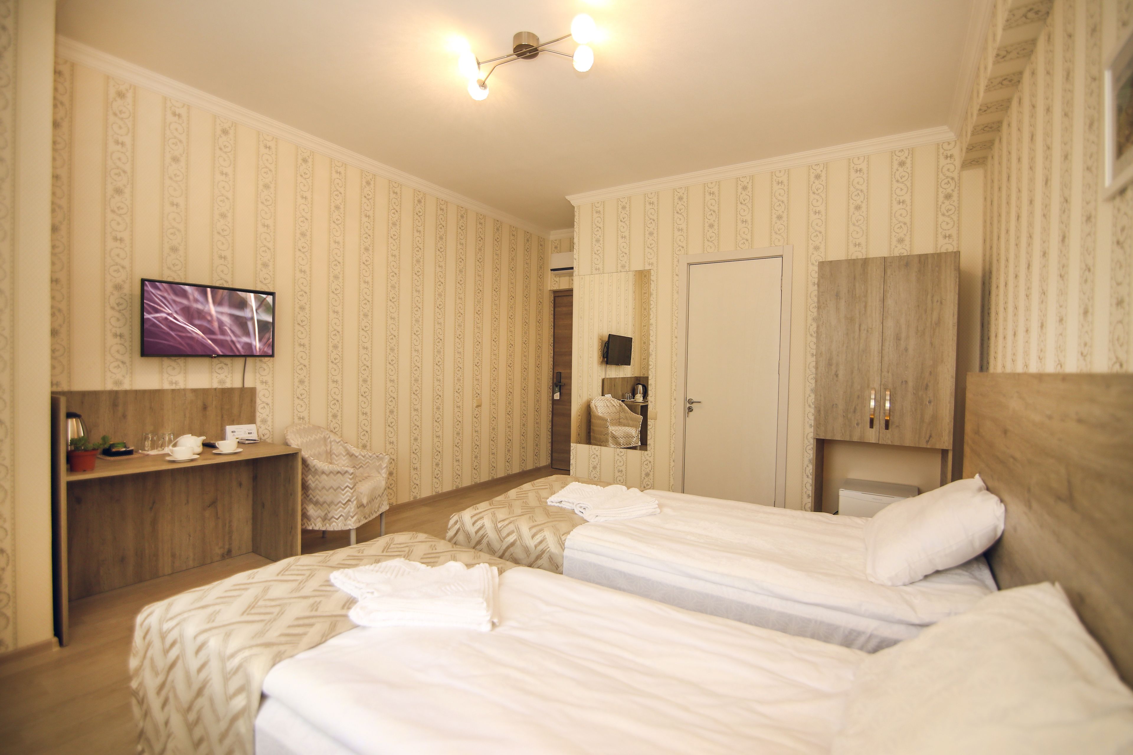 Una habitación de hotel con dos camas, un escritorio con silla, televisor y armario.