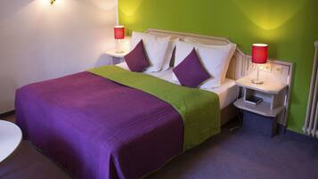 Una habitación de hotel con una cama, dos mesitas de noche, una silla y una pared verde decorativa.