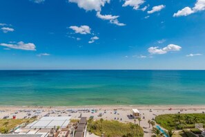 A beach with a clear sky, calm sea, and a view of the beach area including buildings and vegetation. - Hyde Beach Condos by Ammos VR (Hollywood)
