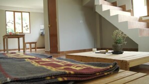 Une pièce avec une table en bois, un tapis à motifs, une petite plante en pot et un escalier.