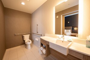 A modern bathroom with a toilet, sink, and mirror.