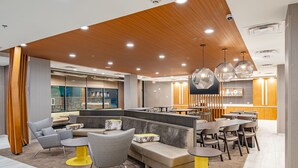 Un espace de détente moderne avec des sièges, un bar et une cuisine en arrière-plan.