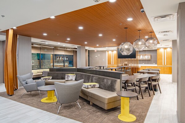 Un espace de détente moderne avec des sièges, un bar et une cuisine en arrière-plan.