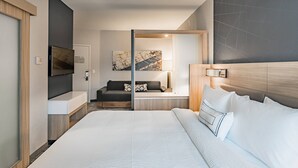 Une chambre d’hôtel moderne avec un grand lit, une télévision, un canapé et un bureau.