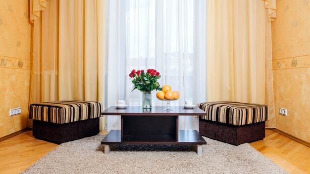A room with a dark wooden table, two cushioned benches, a vase with flowers, and oranges on the table. - Apartments in Nemiga (Minsk)