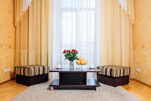 A room with a dark wooden table, two cushioned benches, a vase with flowers, and oranges on the table. - Apartments in Nemiga (Minsk)