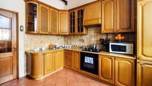 A kitchen with wooden cabinets, a stove, oven, and a microwave. - Apartments in Nemiga (Minsk)