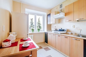 A modern kitchen with wooden cabinets, a stove, and a window with a view of trees. - Apartments in Nemiga (Minsk)