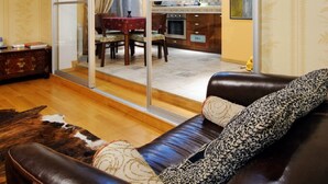 A living room with a leather sofa, a dining area with a table and chairs, and a kitchen visible through a sliding glass door. - Apartments in Nemiga (Minsk)