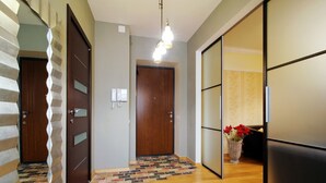 A hallway with wooden flooring, a patterned rug, and a wooden door. - Apartments in Nemiga (Minsk)