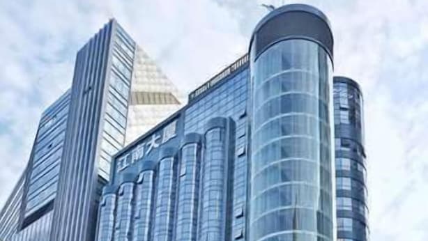 Un immeuble moderne de grande hauteur, doté d’une façade incurvée en verre et d’une structure en forme de pyramide située à gauche.