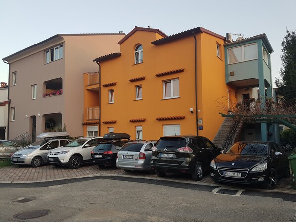A multi-story residential building with a parking area in front.