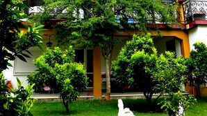 A two-story building with a yellow facade, a balcony with black wrought iron railings, and a well-maintained garden with various shrubs and a white sculpture. - Accommodation Stosic (Rovinj)