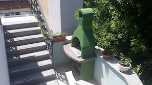 A staircase with a green structure at the bottom, potted plants, and a metal railing.