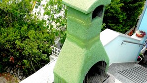 A rooftop with a green, textured structure, possibly a water feature, surrounded by potted plants and flowers. - Accommodation Stosic (Rovinj)
